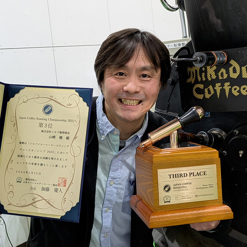 トロフィーと表彰状を掲げた山﨑焙煎士