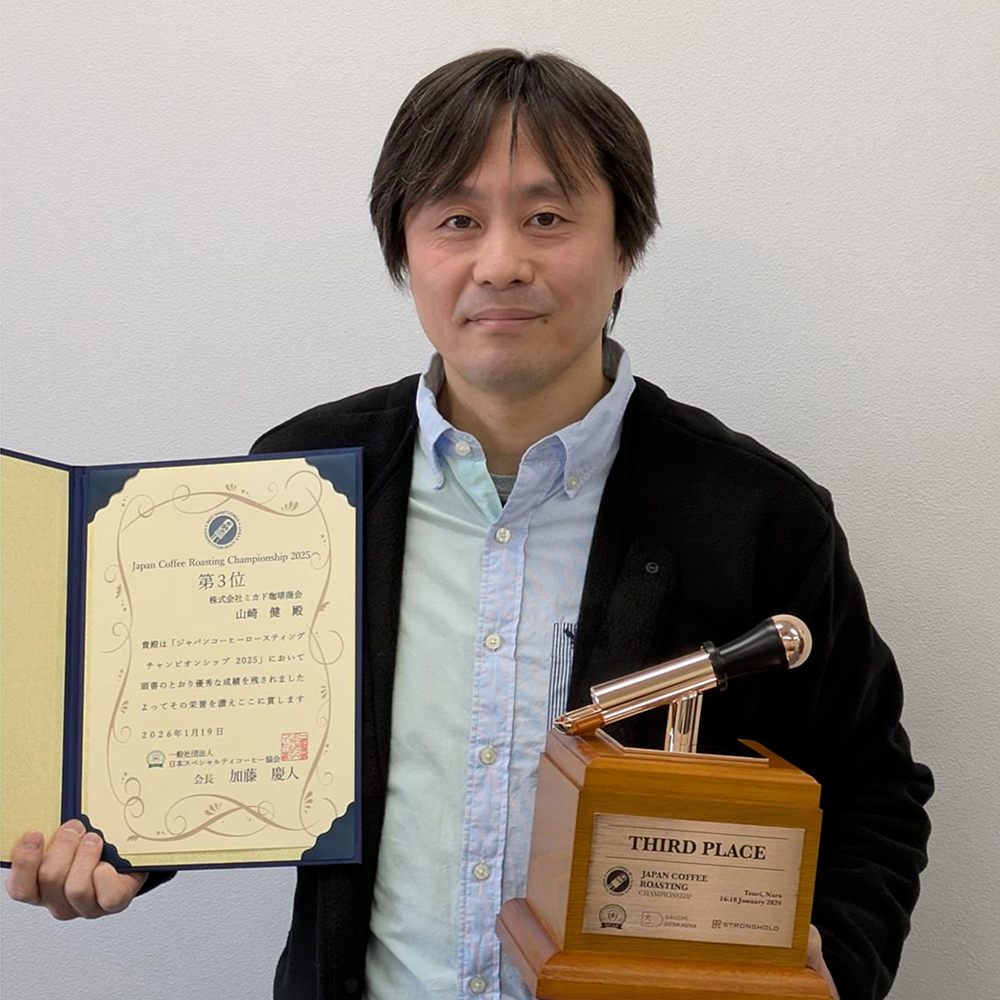 競技会第三位の賞状とトロフィーを胸に誇らしげな山﨑焙煎士
